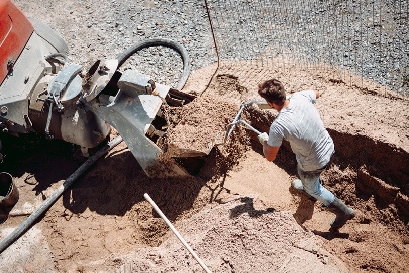 Trabajador de la construcción usando una bomba automática para arena_bogdanhoda_shutterstock